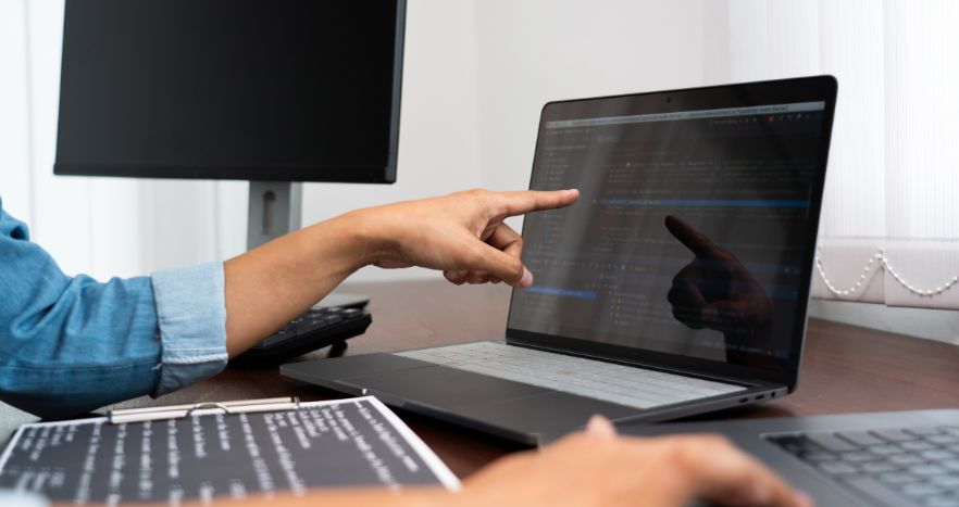 Mulher apontando para a tela de seu computador que sofreu um ataque hacker.