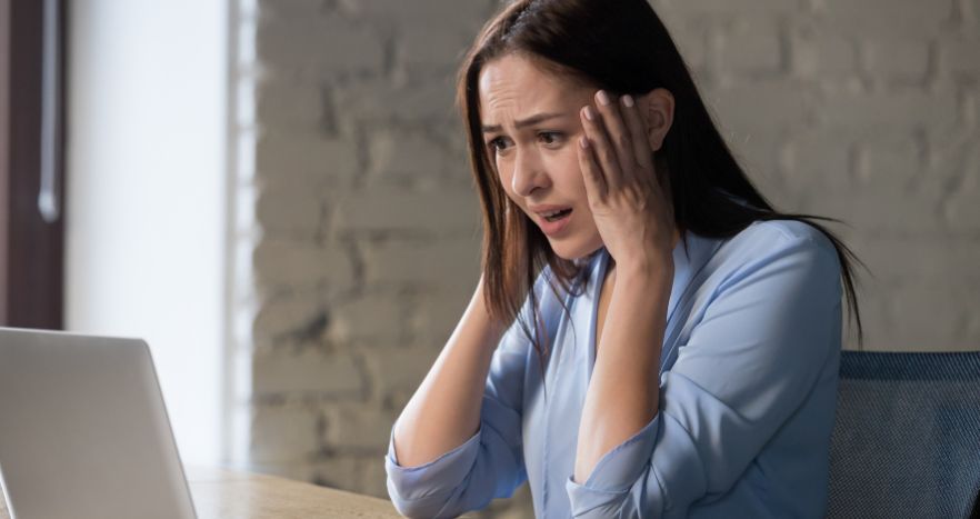 Mulher assustada ao percebeu que caiu em um golpe online por meio de chatbots.